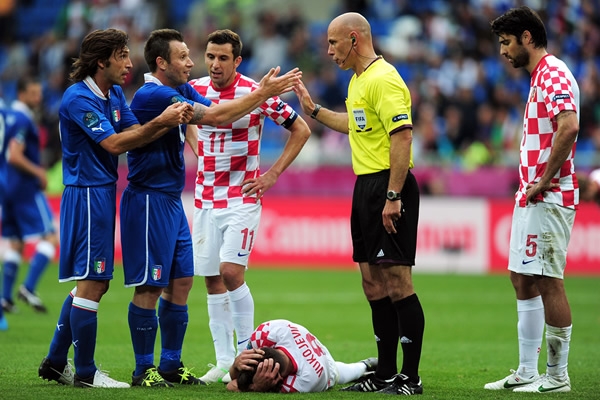El árbitro calmando el ímpetu de los italianos.
