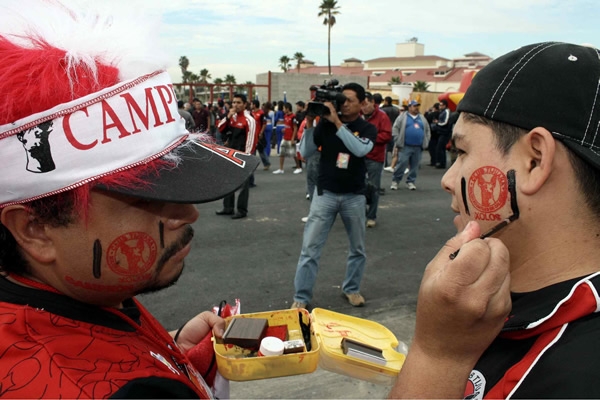 A un aficionado de Xolos le pintan el escudo de su equipo.