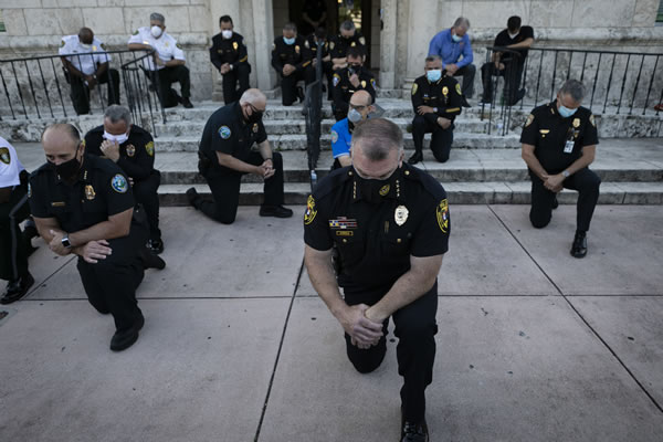 La Policía de Miami se arrodilla ante los manifestantes en señal de apoyo.