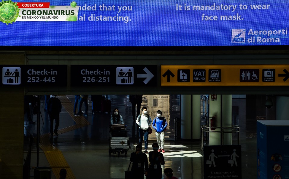 El aeropuerto de Roma muestra indicaciones para que la gente utilice cubrebocas. Foto: AFP