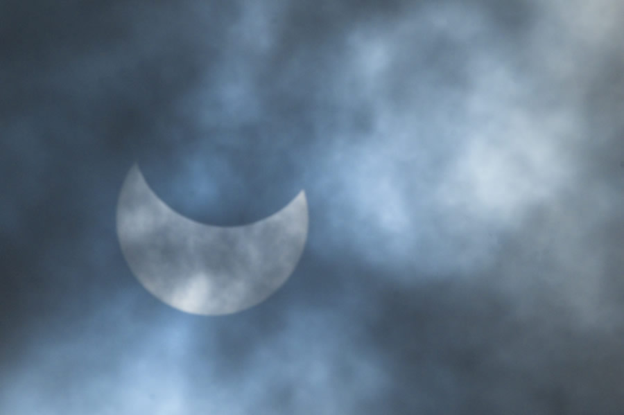 La luna se mueve frente al sol durante un eclipse solar anular visto a través de las nubes en Dhaka. (Foto: AFP)