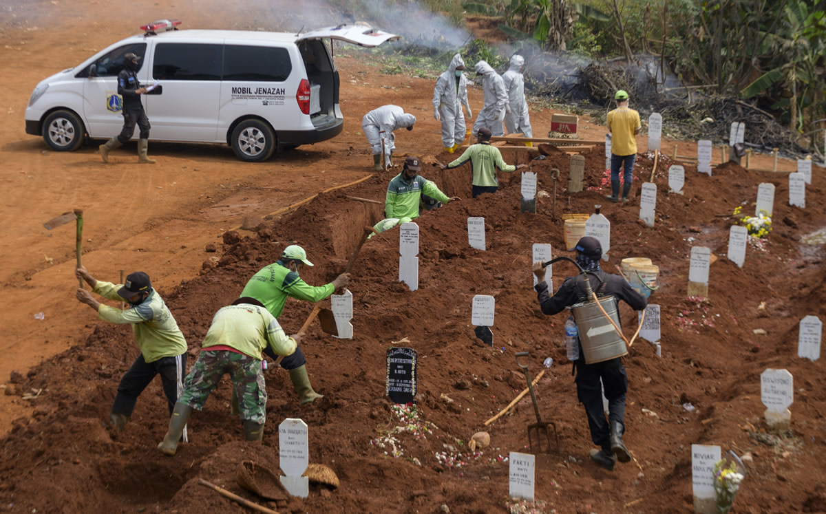 Personas cavan hoyos en un cementerio para las víctimas del coronavirus en Yakarta. (Foto: AFP)