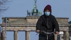 La puerta de Brandemburgo al fondo y un hombre con cubrebocas en la capital Berlín.  Foto: AFP