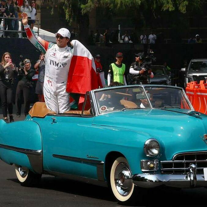 Checo Pérez saluda a la afición de la Fórmula Uno, mientras avanza a un costado de la Diana Cazadora, en Paseo de la Reforma. FOTO: Reuters